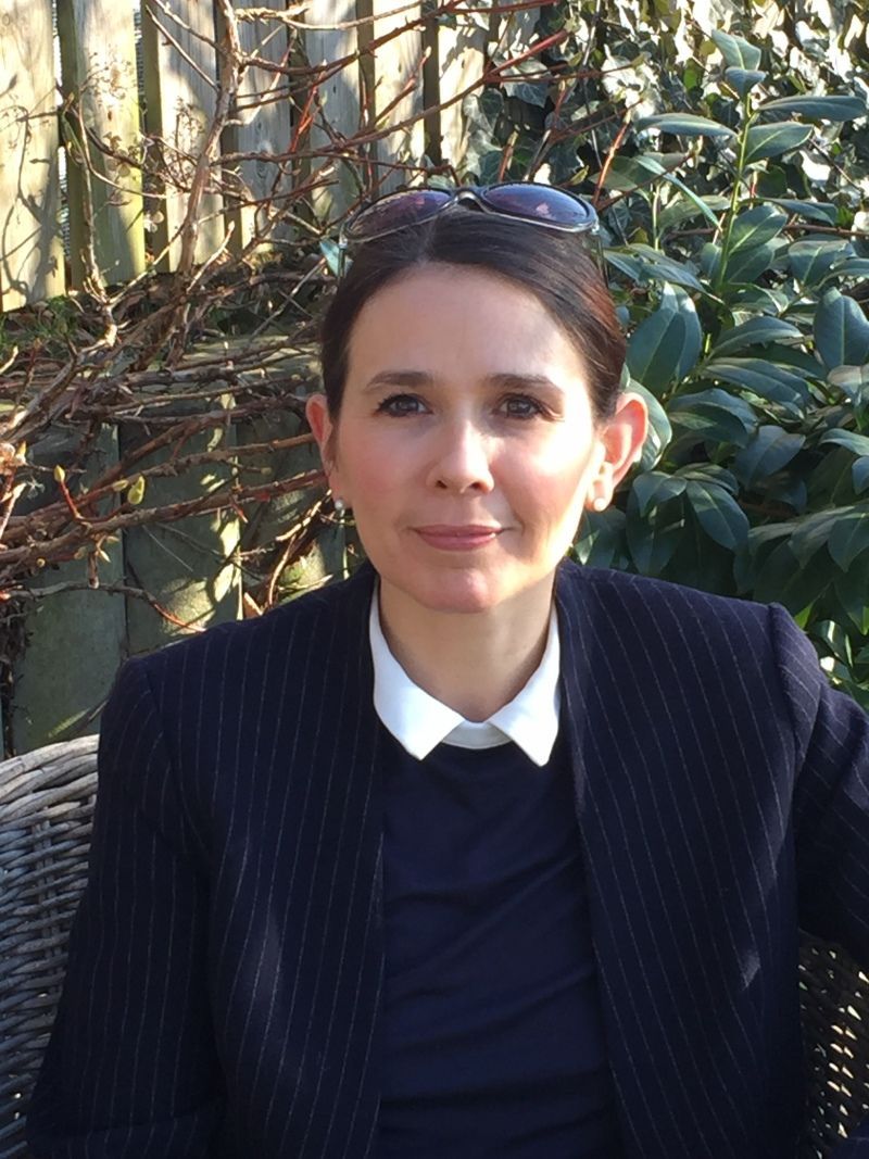 Porträt von Karoline Pfaff im Freien vor grünen Pflanzen, sie blickt in die Kamera.