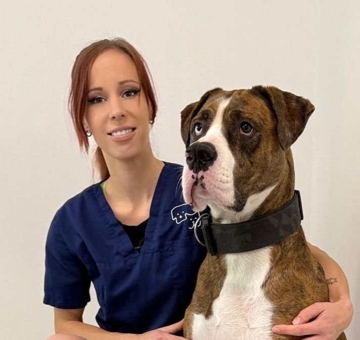 Porträt von Nadine Schlieb vor hellem Hintergrund, neben ihr sitzt ein brauner Hund.