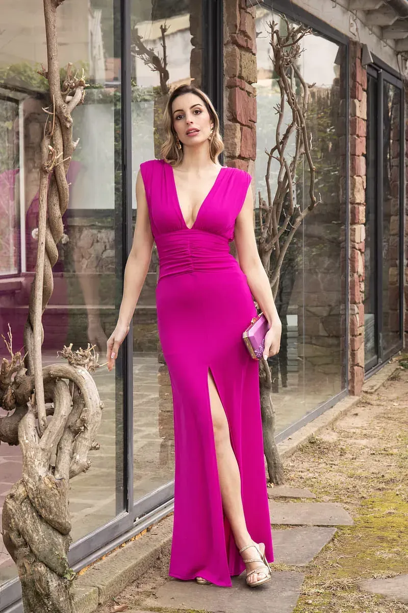 Una mujer con un vestido largo de color rosa está parada frente a un edificio.