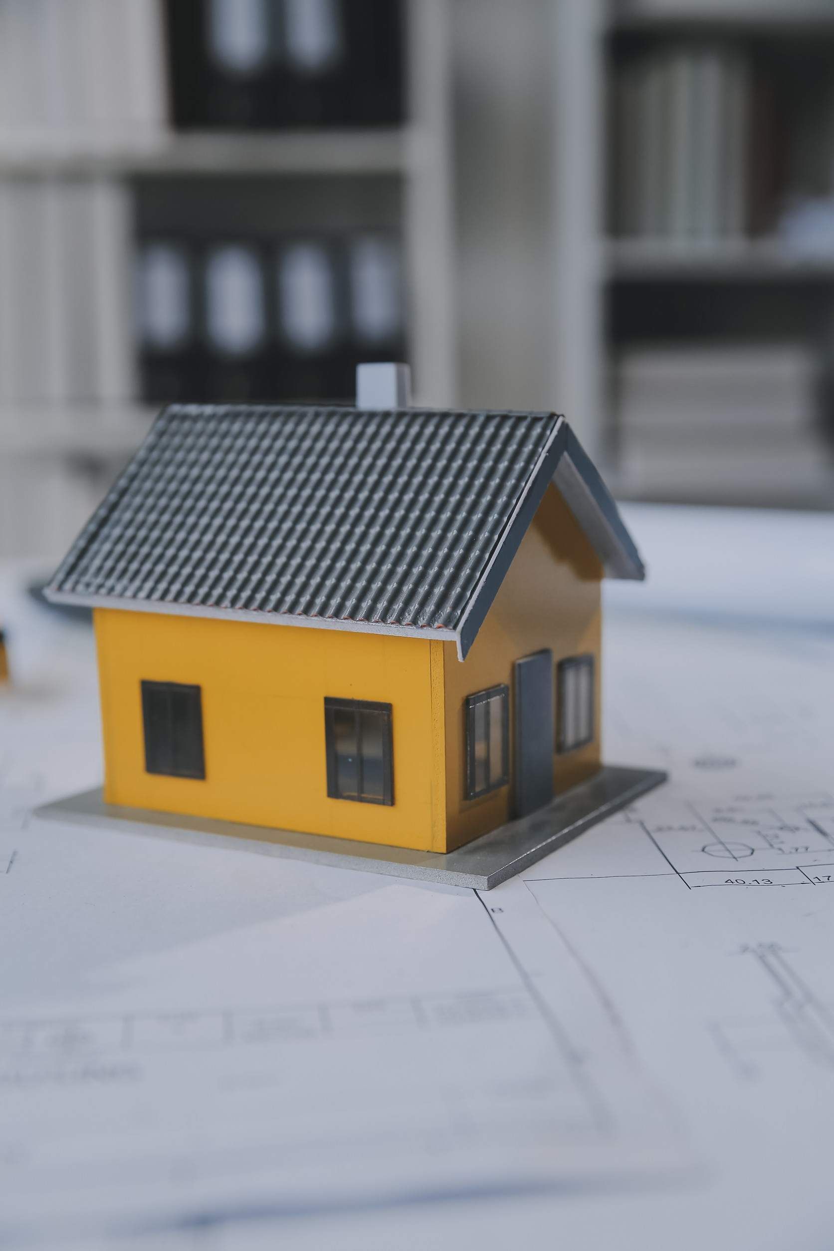 Una pequeña maqueta de casa está colocada encima de un plano.