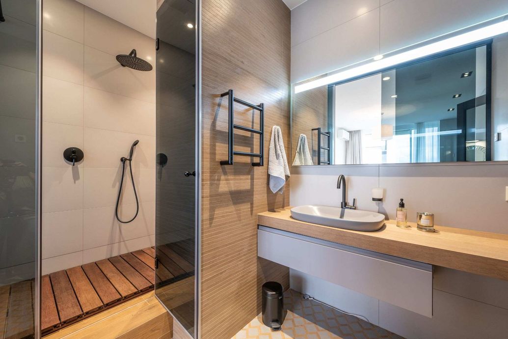 Un baño con lavabo, ducha y espejo.