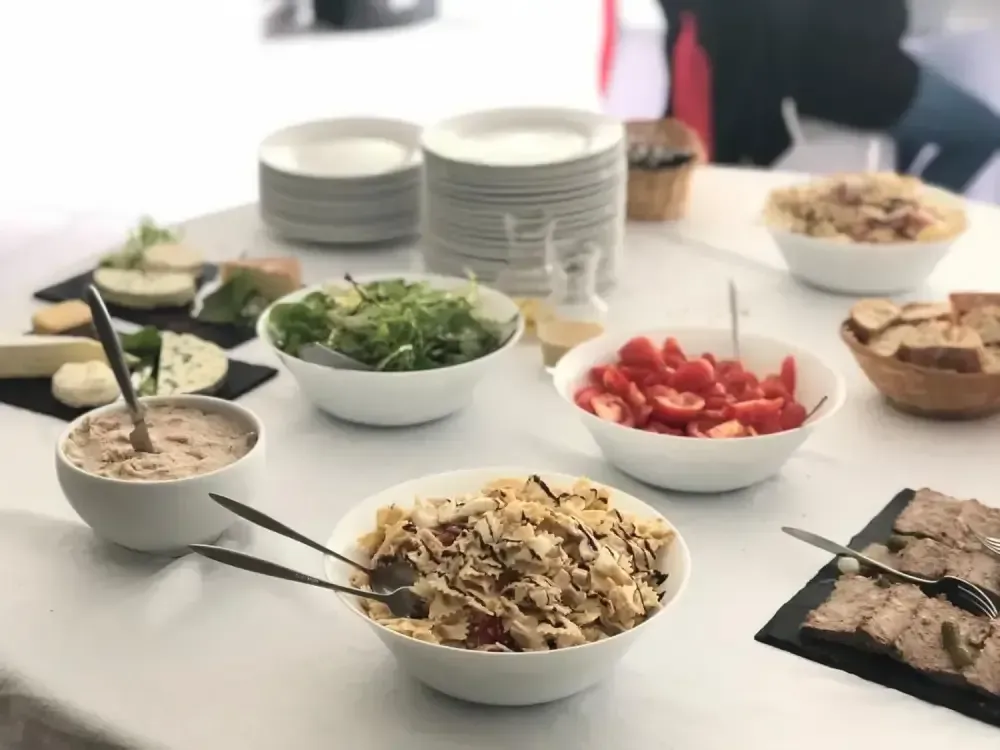 Buffet avec des saladiers, des tomates en tranches, de la viande grillée et des sauces.