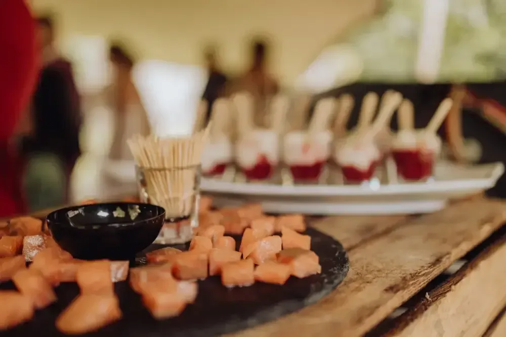 Entrées servies sur une assiette noire, avec un pot à cure-dents, sur une table de buffet de restaurant floue
