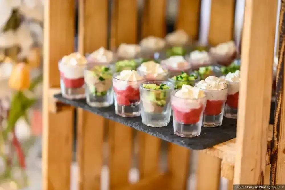 Des coupes de dessert garnies de crème fouettée et de baies, disposées sur une étagère en bois dans un buffet