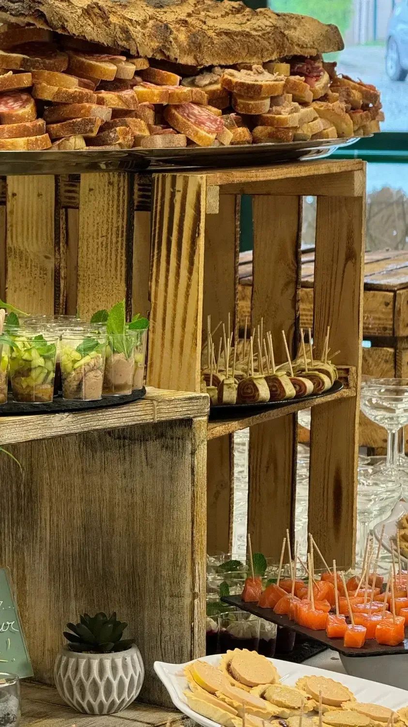 Présentoir à desserts rustique avec des pâtisseries et des boissons colorées sur des étagères en bois en plein air