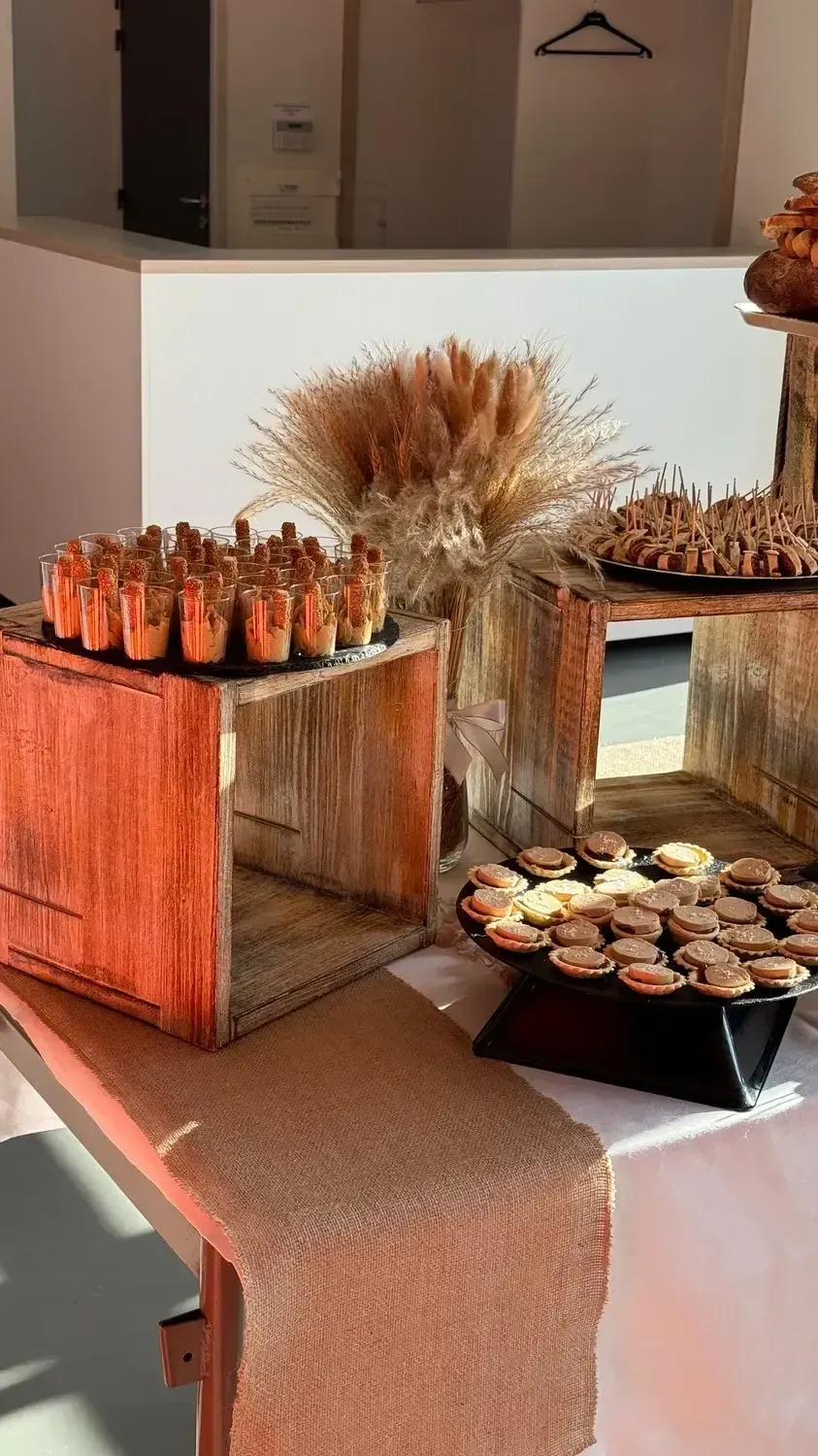 Table de desserts avec des cupcakes, des fleurs séchées et une décoration rustique en bois sur une nappe blanche.