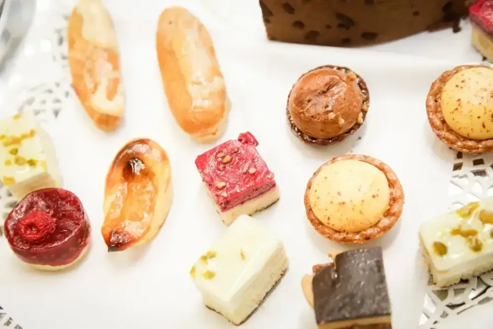 Assortiment de petits fours et de macarons colorés sur une assiette blanche parsemée de paillettes dorées