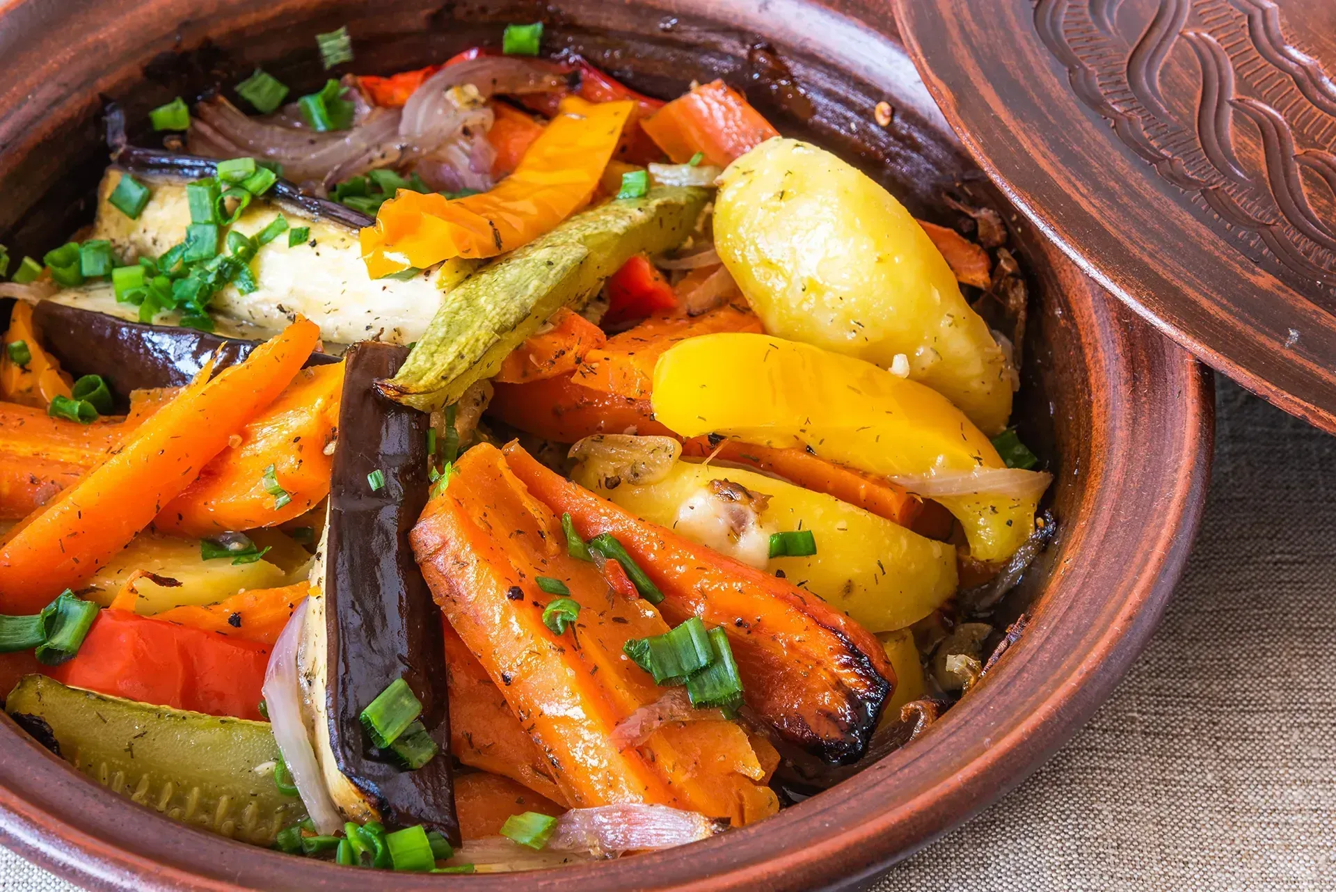 Ragoût de légumes coloré dans un pot en terre cuite, avec des carottes.