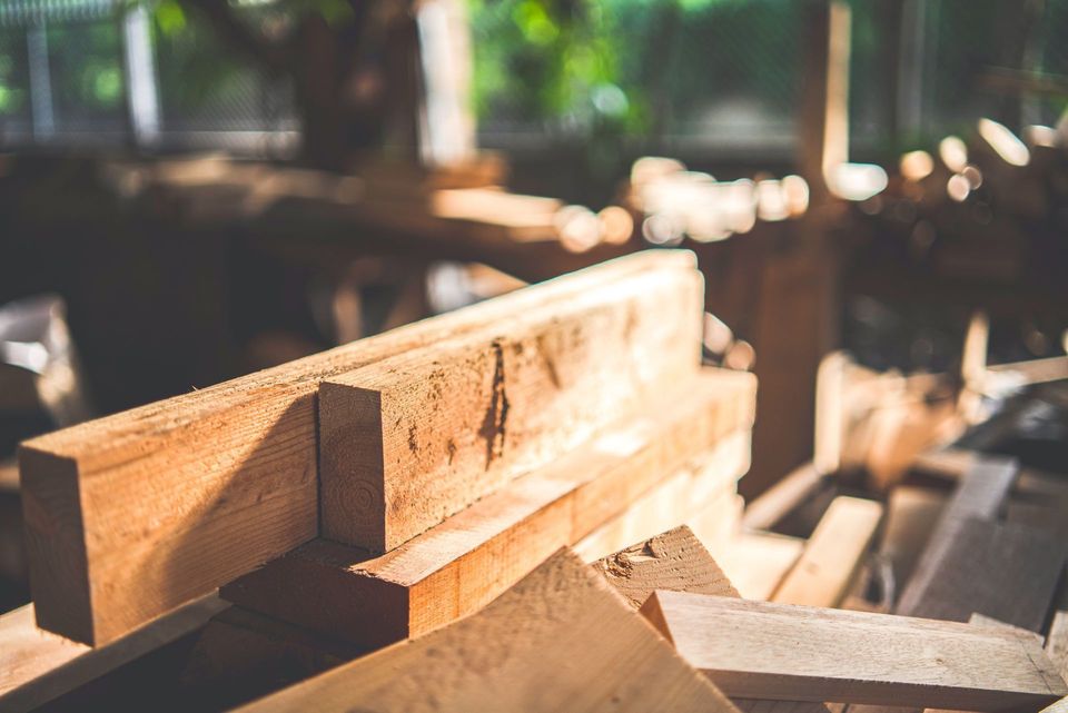 Des planches de bois empilées sous le soleil chaud d'une scierie ou d'un atelier.