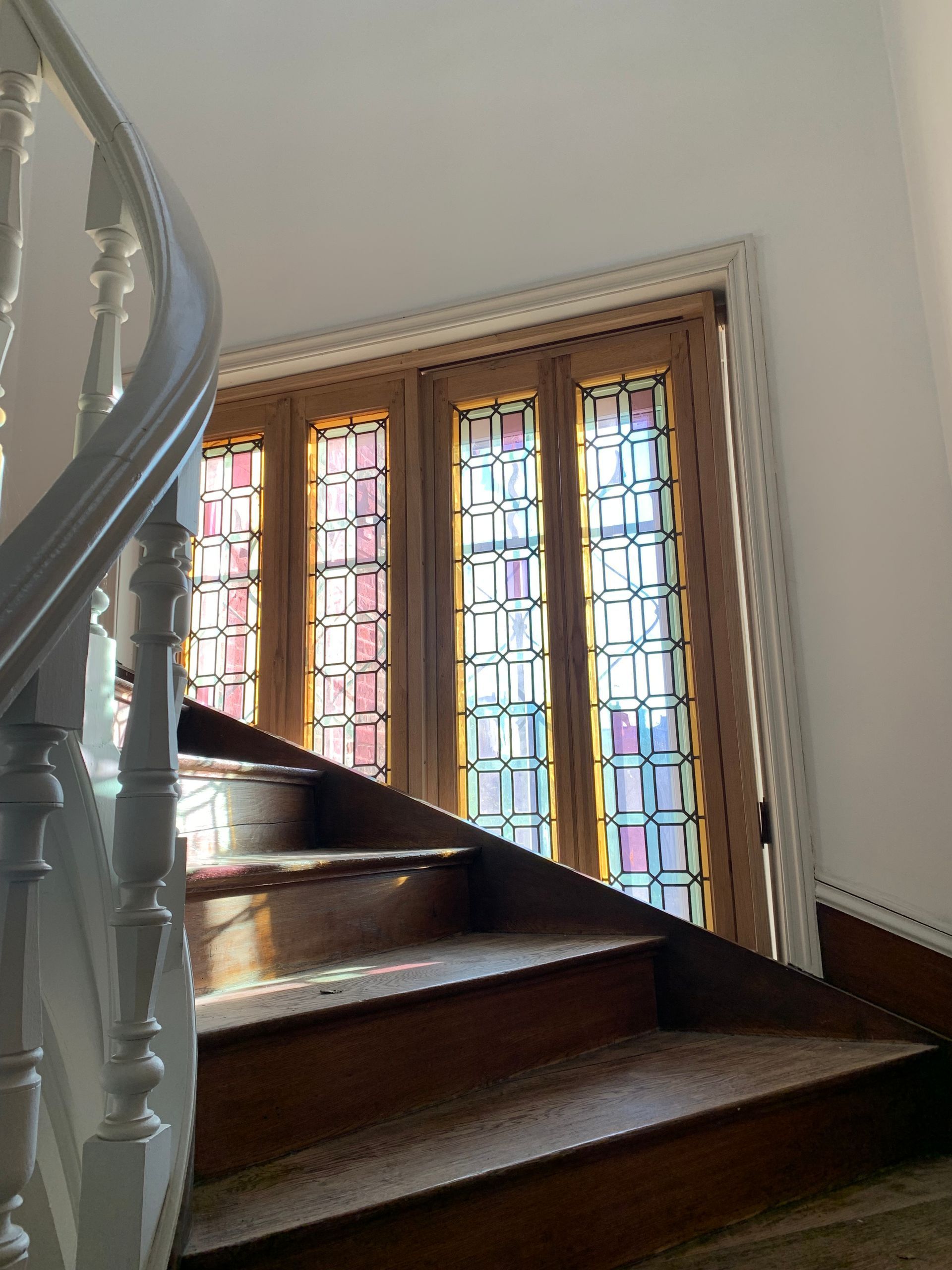 Escalier en bois courbe à côté de vitraux dans un intérieur lumineux