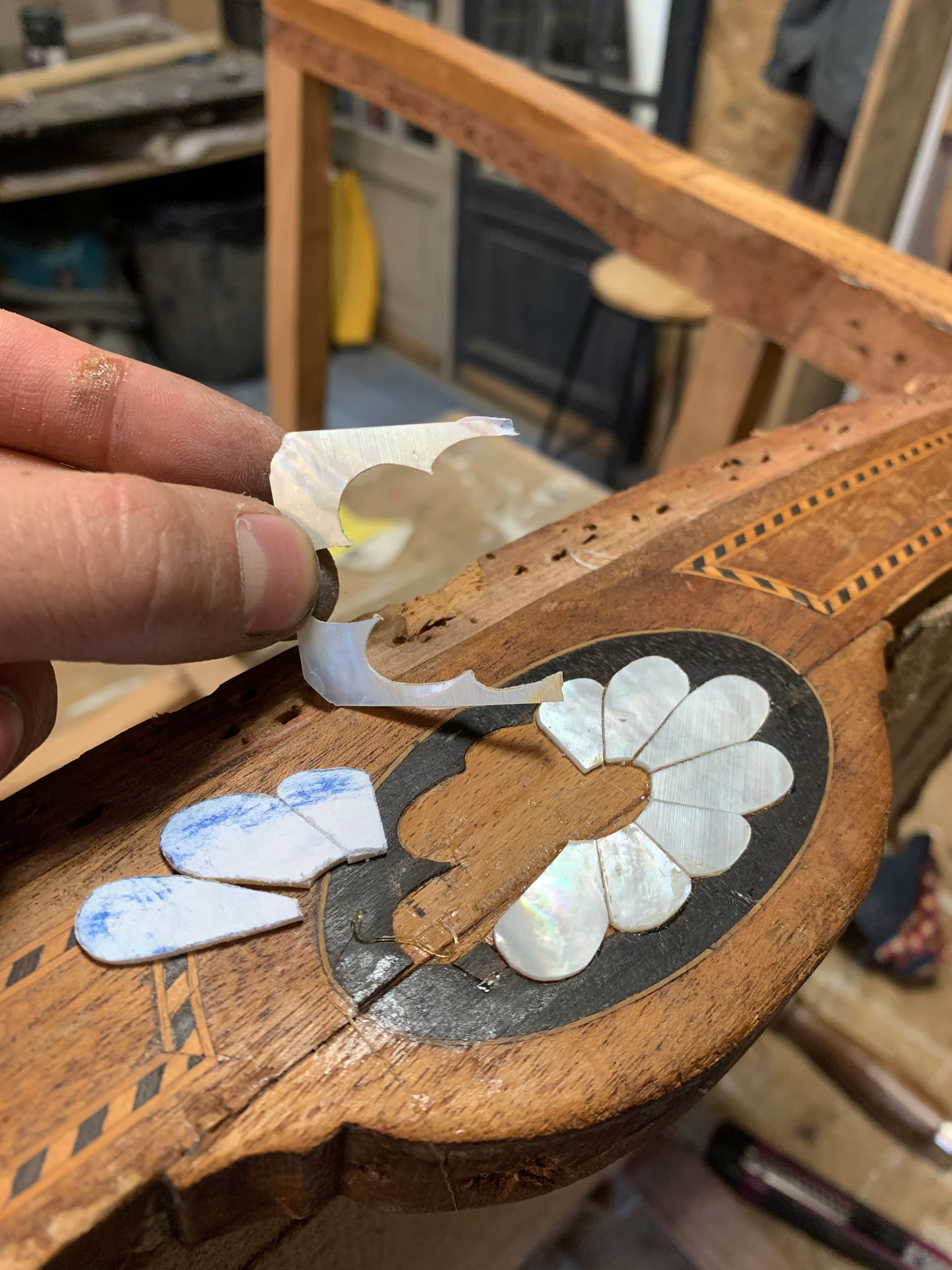 Pose manuelle de pièces incrustées de coquillage blanc dans un cadre de chaise en bois lors de la réparation de meubles
