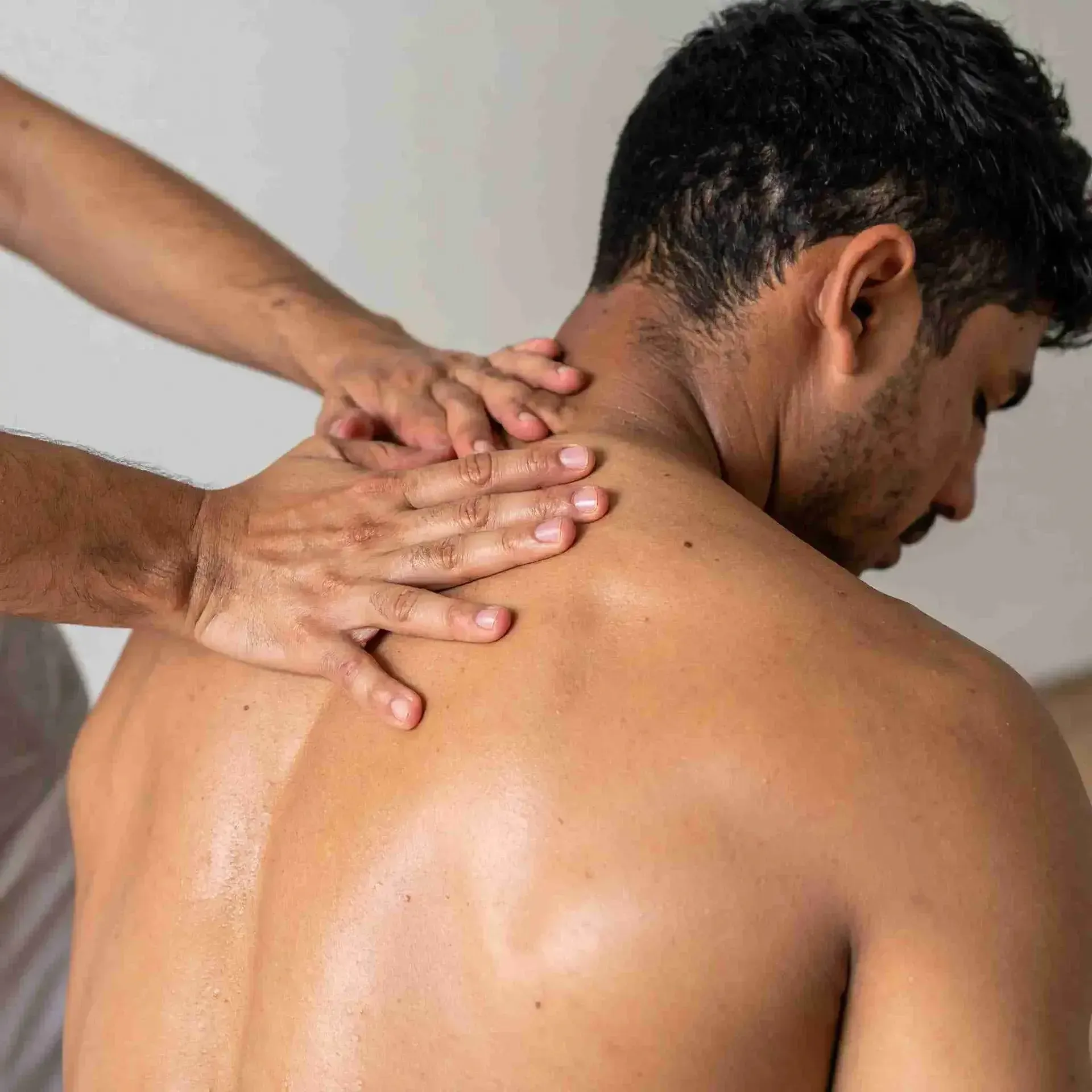 Hombre recibiendo un masaje de hombros; manos en el cuello y la espalda.