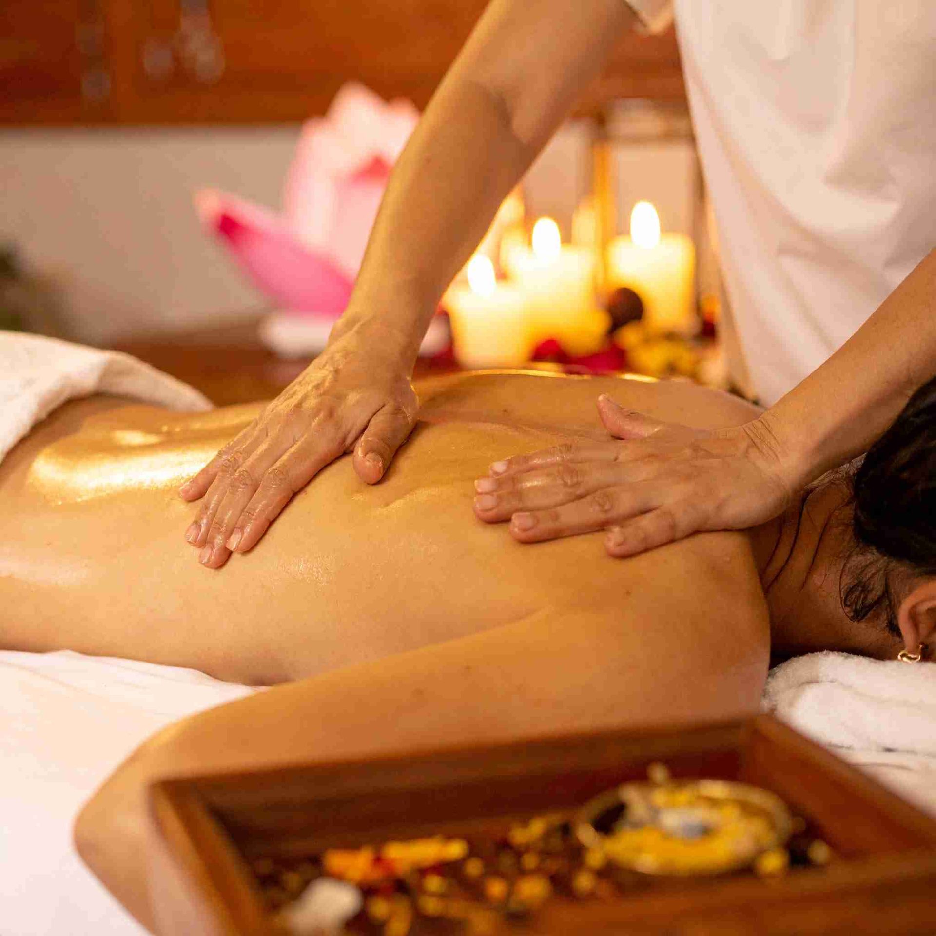 Persona recibiendo masaje de espalda, velas encendidas de fondo.