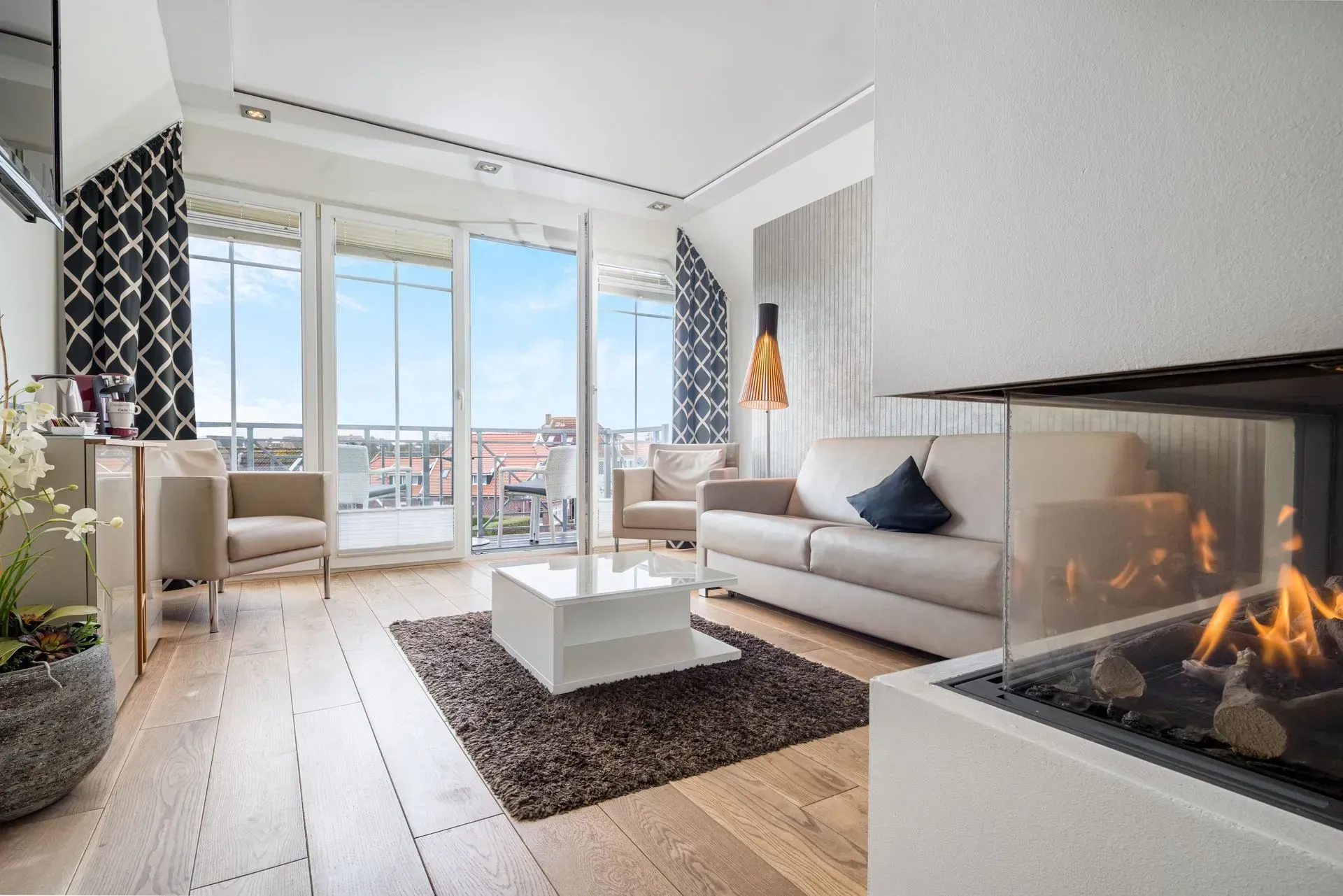 Wohnzimmer mit modernem Design, Holzböden, Kamin und Zugang zum Balkon.