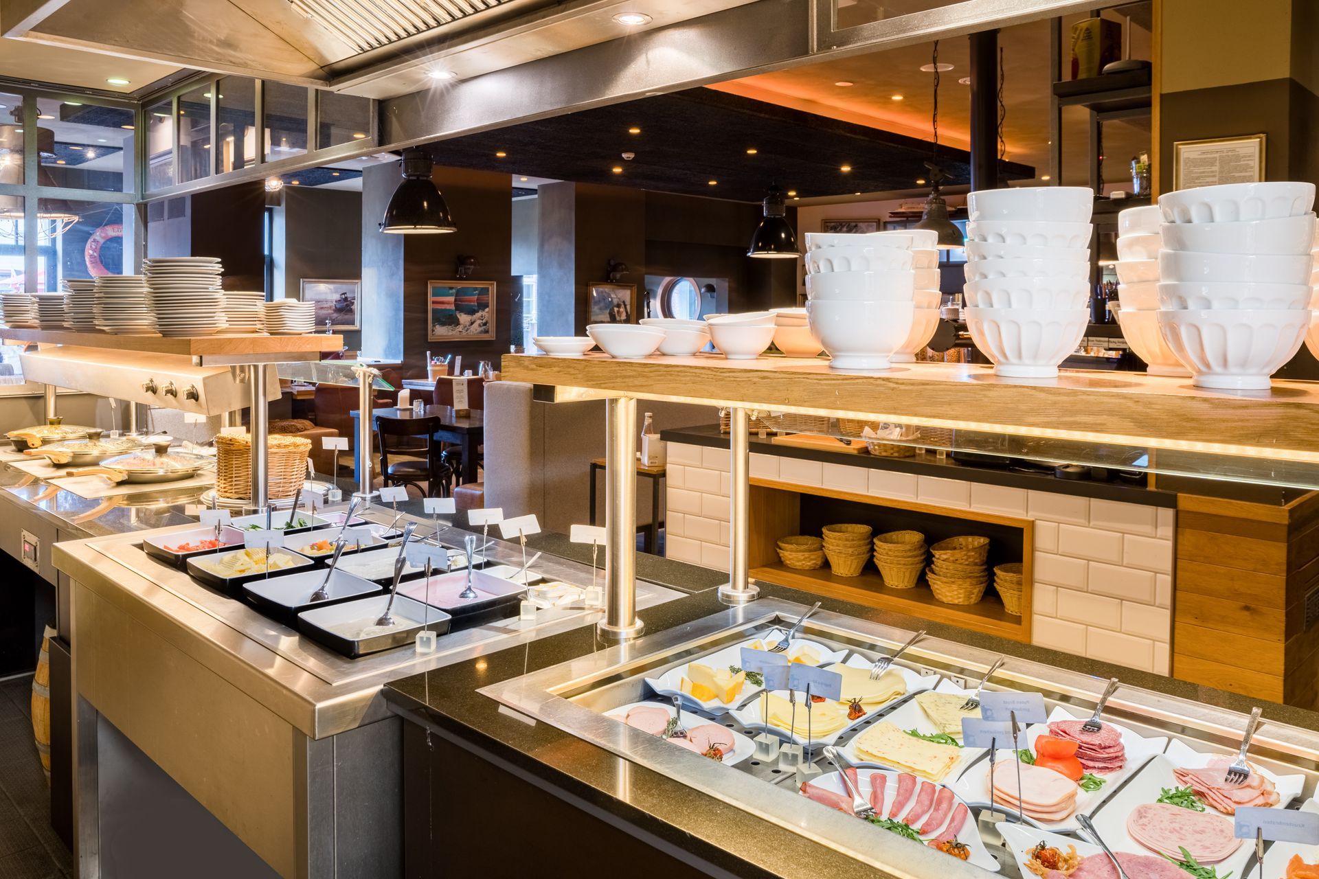 Buffet mit einer vielfältigen Auswahl an Speisen, beleuchtet durch Deckenleuchten in einem Restaurantambiente.