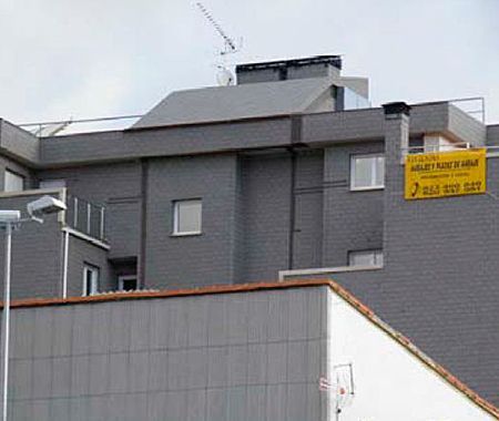 Un gran edificio gris con un cartel amarillo al costado.