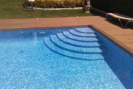 Una piscina con escaleras que conducen a ella y una terraza de madera.