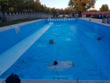Una piscina vacía con agua azul y un borde blanco.