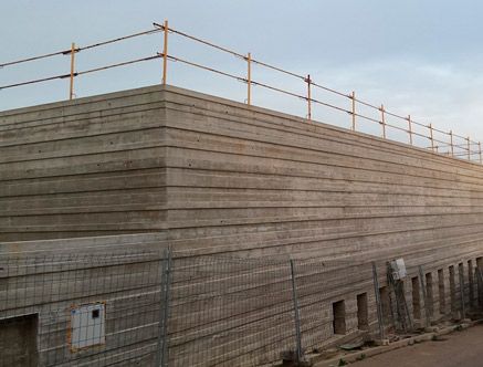 Un gran muro de hormigón con una valla metálica a su alrededor.