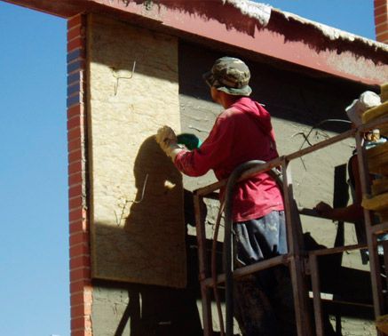 Un hombre con una camisa roja está trabajando en un edificio.