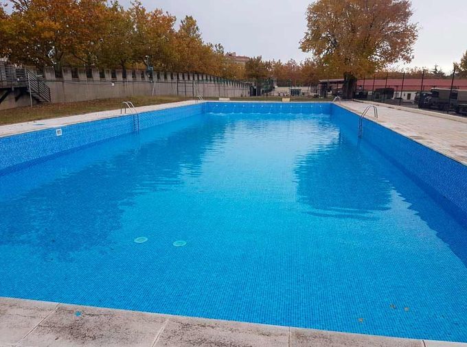 Una gran piscina azul con árboles al fondo.