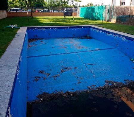 Una piscina azul vacía con una manguera al costado