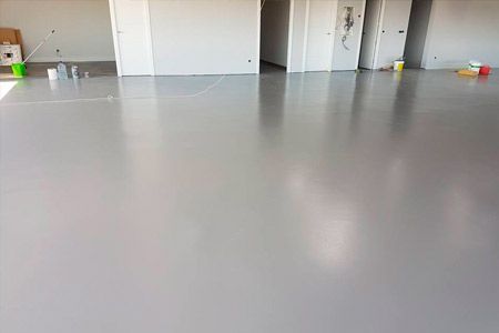 Una habitación grande con suelo gris y paredes blancas.