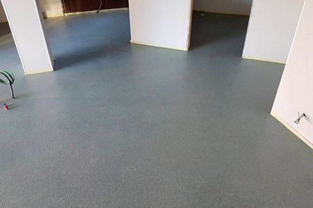 Una habitación con suelo gris y paredes blancas.