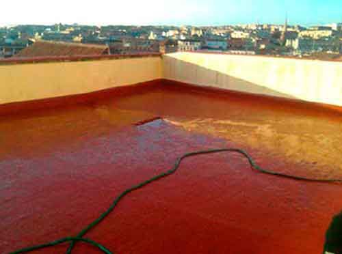 Un techo rojo con una manguera encima y una ciudad al fondo.