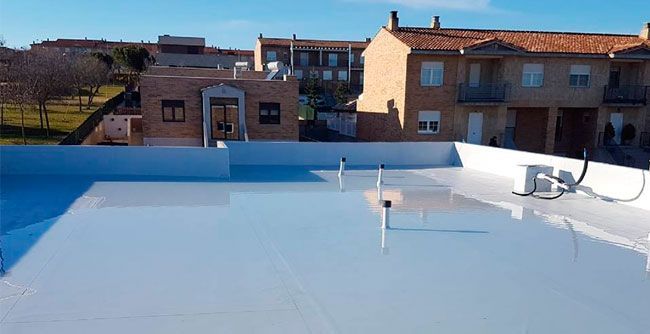 Un techo blanco con una antena parabólica delante de una hilera de casas.