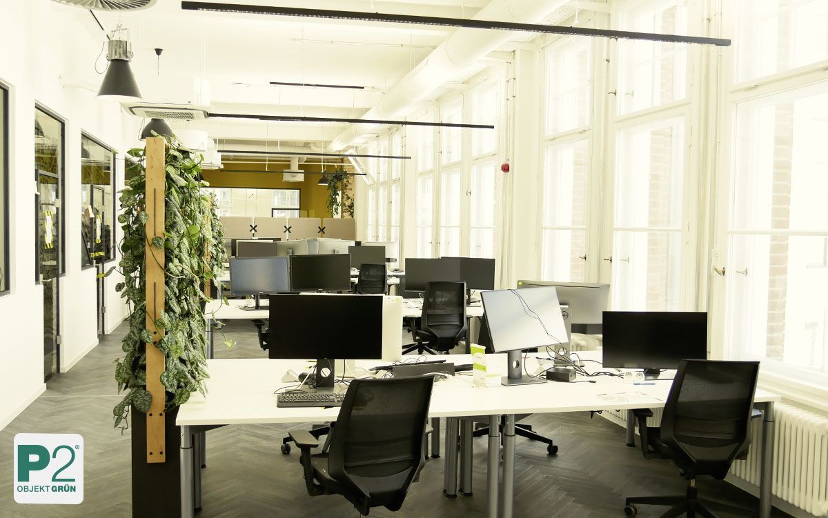 Modernes Büro mit großen Pflanzen und runden Tischen.