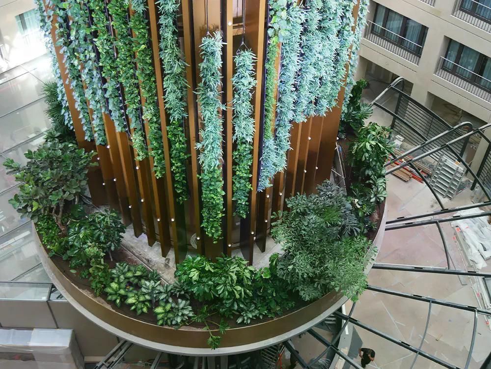 Innenansicht eines modernen Gebäudes mit vertikalen Pflanzen und grünen Elementen.