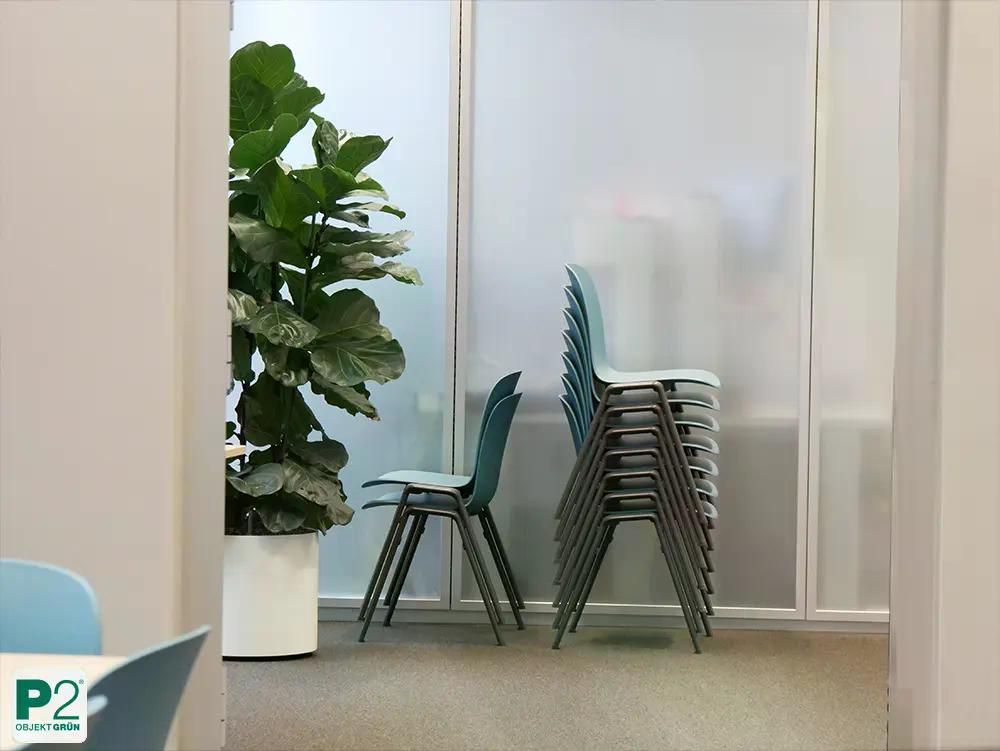 Eine dekorative rosa Vase mit leuchtend gelben Zitronen und grünen Blättern, umgeben von lebhaften Blumen und Blättern.