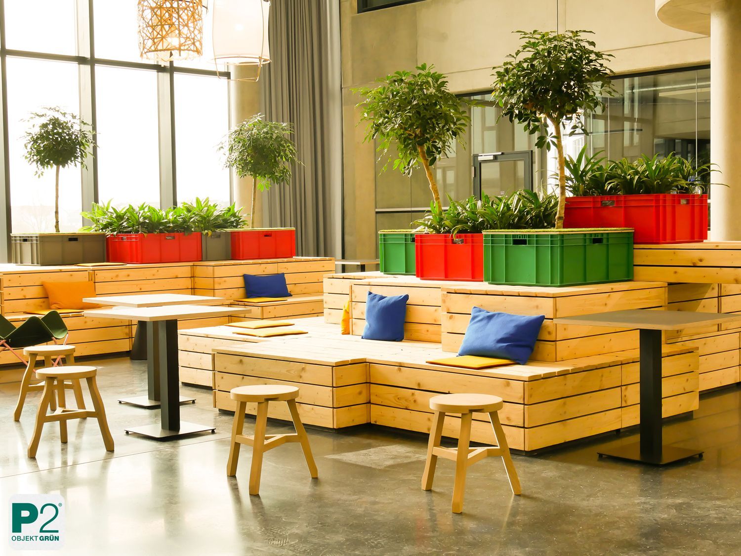 Moderne Lounge mit Holzsofas, blauen Kissen, grünen und roten Pflanzkästen und Hockern in hellem Raum