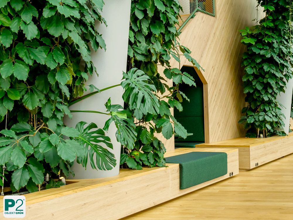 Moderne grüne Wandgestaltung mit Pflanzen und Holzoberflächen.