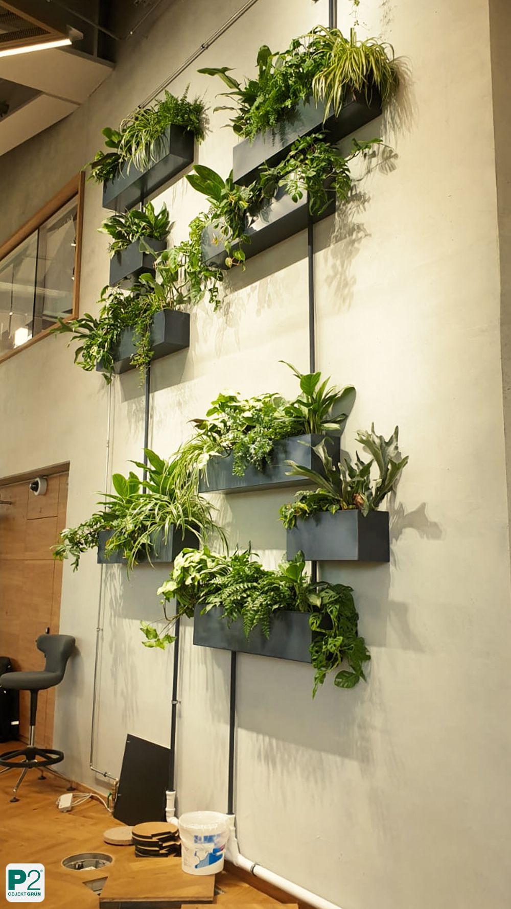 Moderne Wandbegrünung mit verschiedenen Pflanzen in Töpfen.