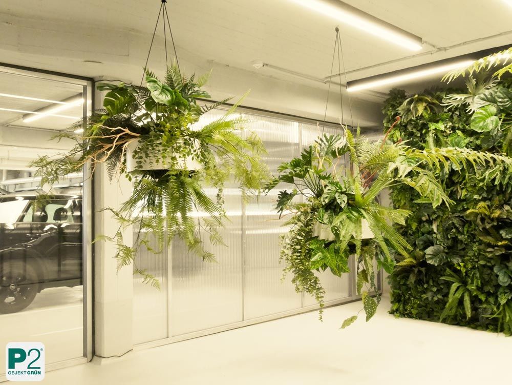 Pflanzeninstallationen an Glaswänden eines modernen Büros mit hellen Wänden.