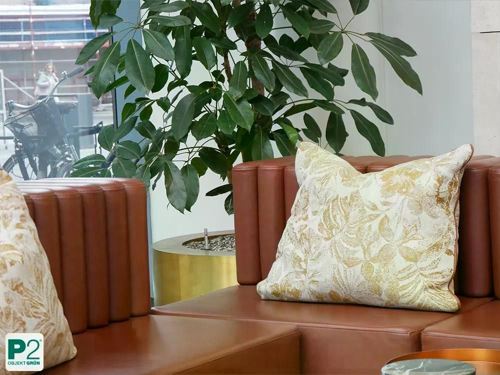 Ein gemütliches Kissen mit einem eleganten Blattmuster auf einer Ledercouch.