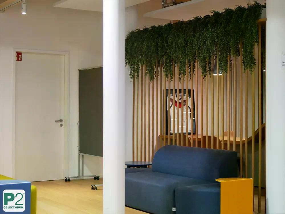 Ansicht eines modernen Büros mit grünen Pflanzen und stilvollem Sofa.