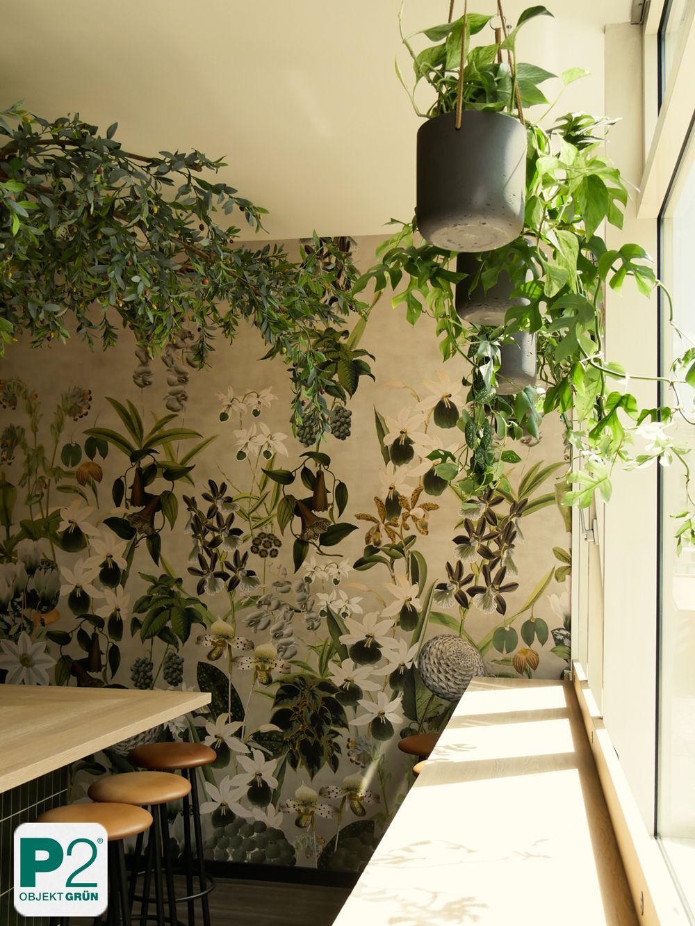 Helle Sitzecke mit Holzstühlen, Wand mit floralem Muster und hängenden grünen Pflanzen am Fenster