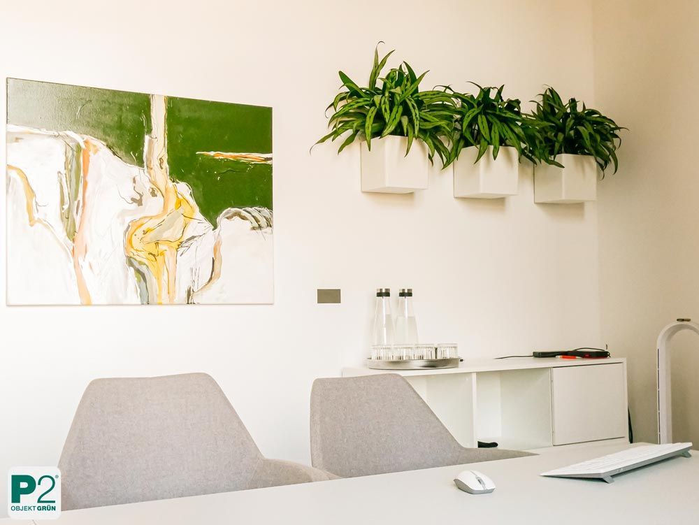 Modernes Büro mit zwei grauen Stühlen, abstraktem Kunstwerk und drei Wandpflanzen in weißen Behältern