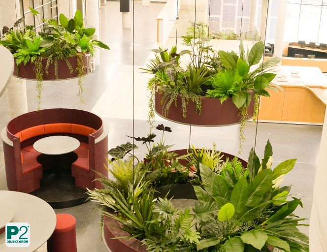 Moderne Sitzinsel im Atrium mit runden Pflanzgefäßen und viel natürlichem Licht.