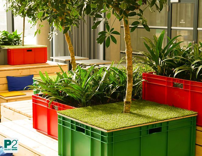 Arbeitsbereich mit Holzmöbeln und bunten Pflanzkübeln voller grüner Pflanzen.