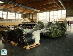 Indoor-Trainingsplatz mit gestapelten Pflanzkübeln und verpackten Bäumen auf Paletten, vorbereitet für Begrünung