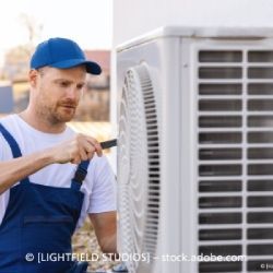 Ein Mann repariert eine Klimaanlage mit einem Schraubenzieher.