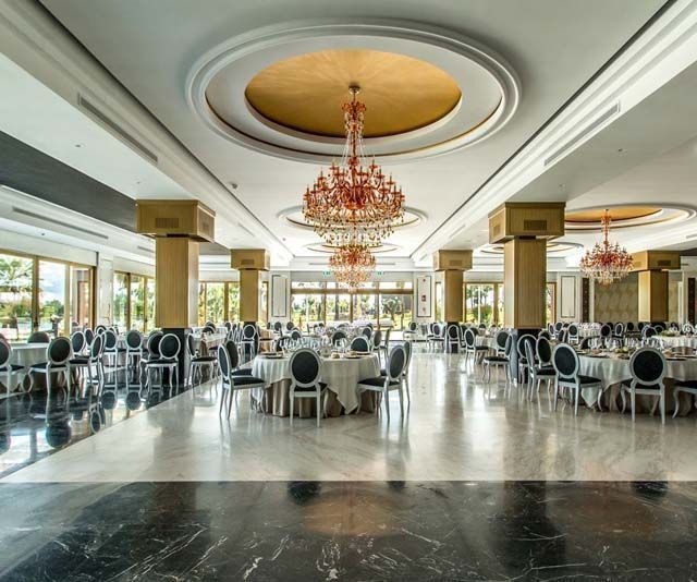 Un gran comedor con mesas y sillas y una lámpara de araña.