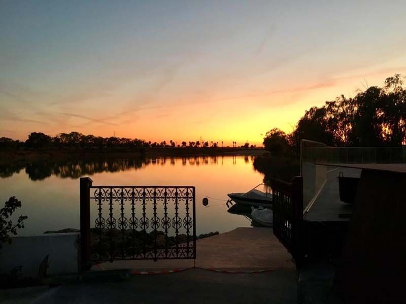 Una puesta de sol sobre un lago con una puerta en primer plano
