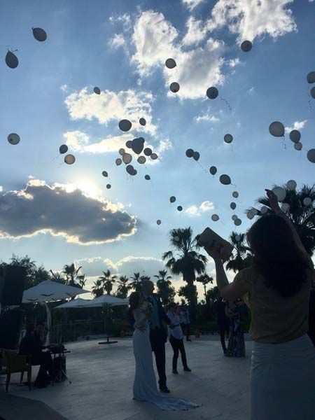 Una novia y un novio están lanzando globos al cielo.