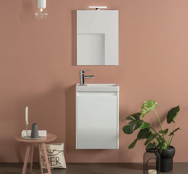 Un baño con lavabo, espejo y una planta.