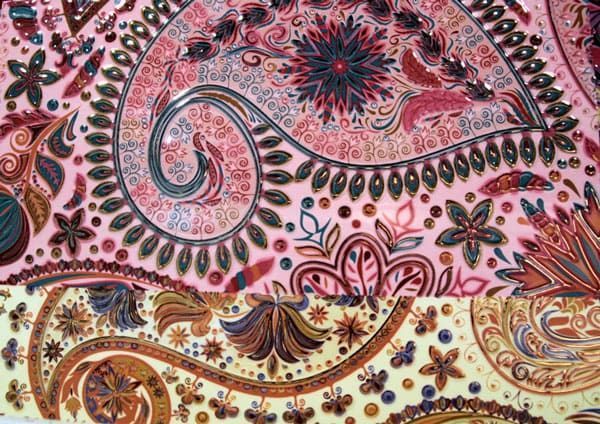 Un primer plano de un patrón paisley rosa y amarillo sobre un trozo de tela.